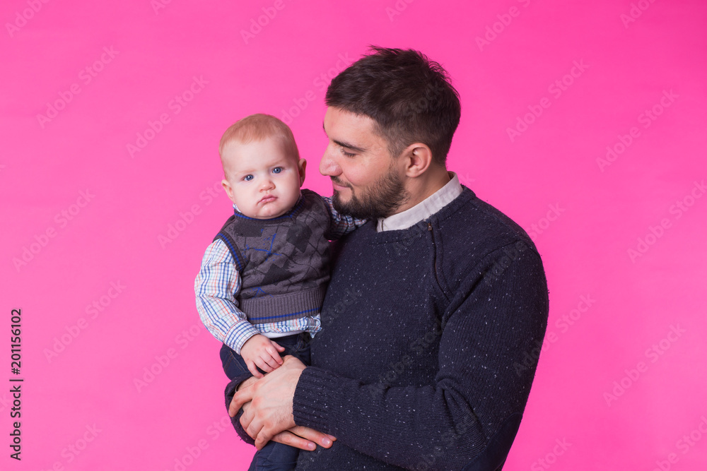 happy father with a baby son isolated on a pink background