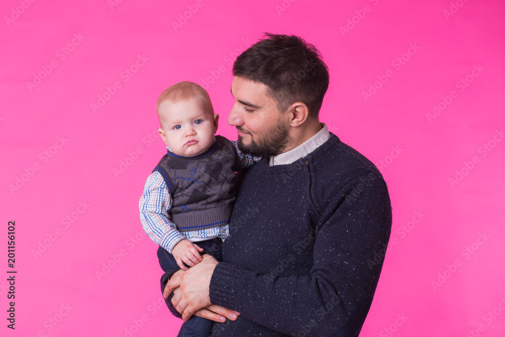 happy father with a baby son isolated on a pink background happy father with a baby son isolated on a pink background