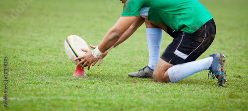 rugby player preparing to kick the oval ball during game