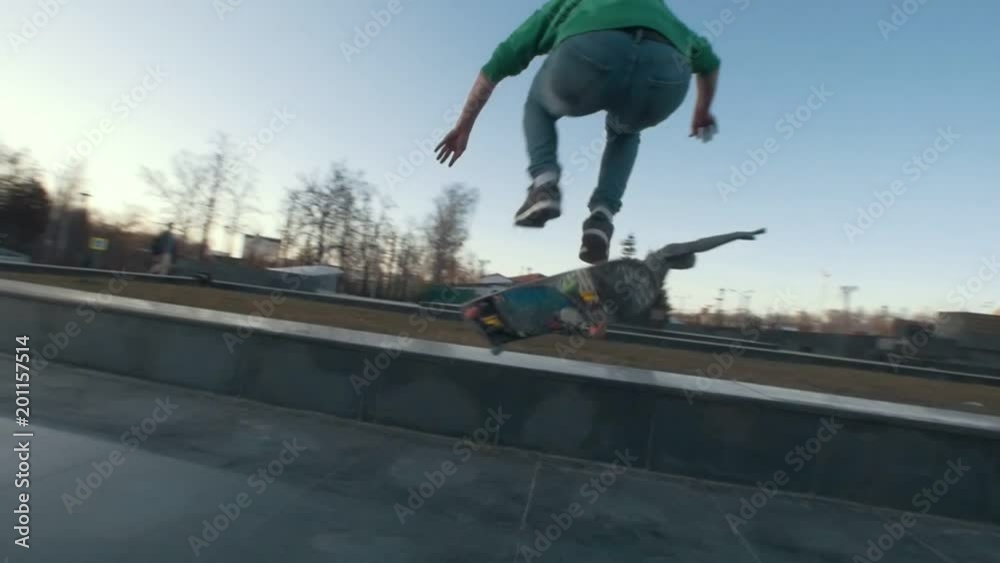 Skateboarder performs tricks on the ramp outdoors in sunset