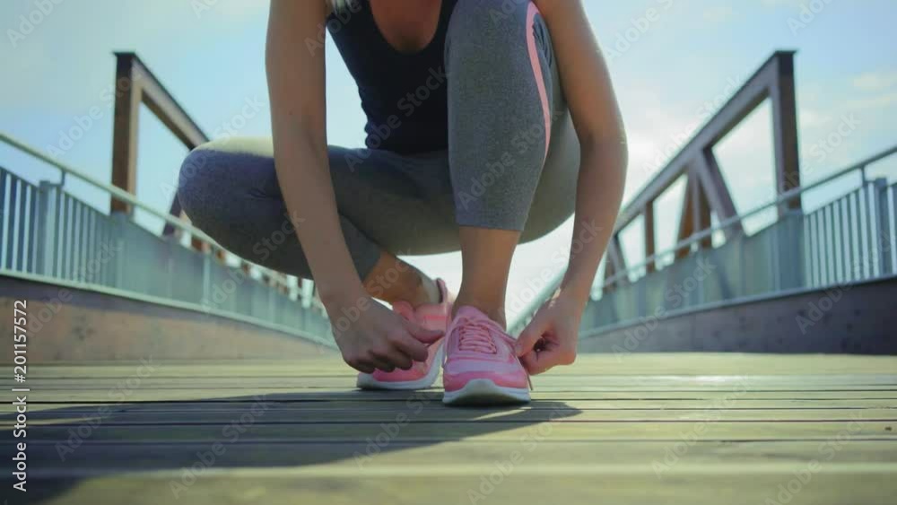 Running woman. Girl run and jogging training close-up sneakers in bridge background in sunny day