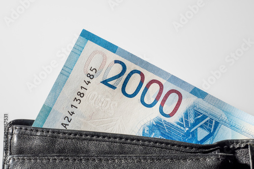 Black natural leather wallet isolated on white background. Expensive man's purse closeup. New russian ruble banknote, Two thousand rubles.