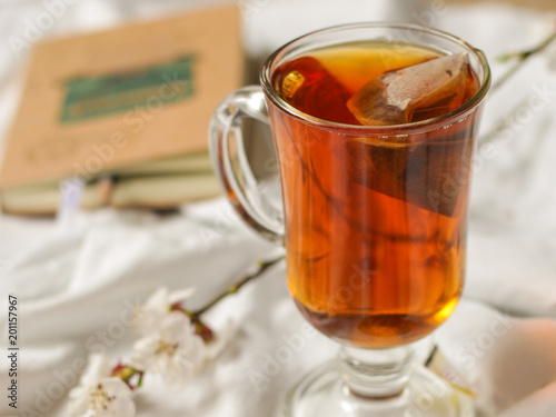 tea brew in a cup (tea bag) on ​​the table and flowering spring twigs. Food background - drink background