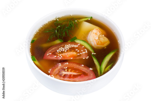 Asian soup. Soup in a plate isolated on white background. Seafood soup with shrimps, tomatoes and tofu cheese.