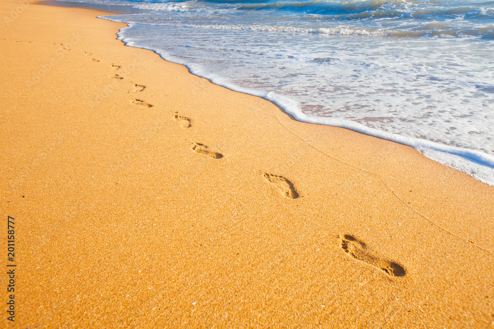 beach, wave and footprints at sunset time