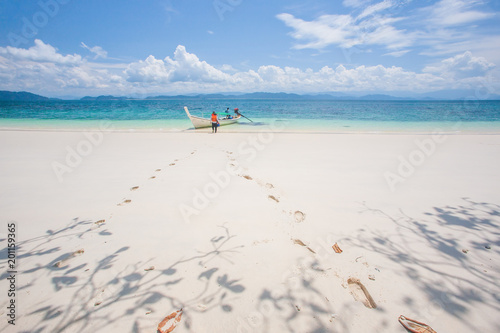 Footprints and tourists on a beach in summer.