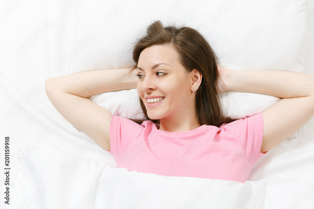Top view of happy brunette young woman lying in bed with white sheet, pillow, blanket, hands under head. Smiling female spending time in room. Rest, relax, good mood concept. Copy space advertisement. Top view of happy brunette young woman lying in bed with white sheet, pillow, blanket, hands under head. Smiling female spending time in room. Rest, relax, good mood concept. Copy space advertisement.