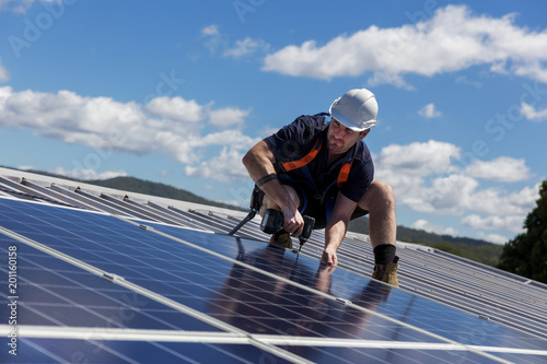 Solar panel technician with drill installing solar panels photo