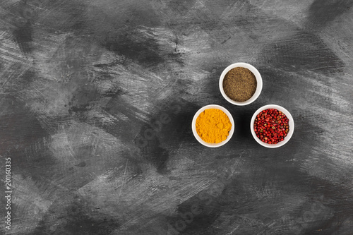 Various spices in bowls on black background. Top view, copy space. Food background