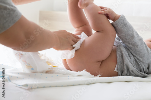 Fototapet Diaper changing and cleaning bottom of baby