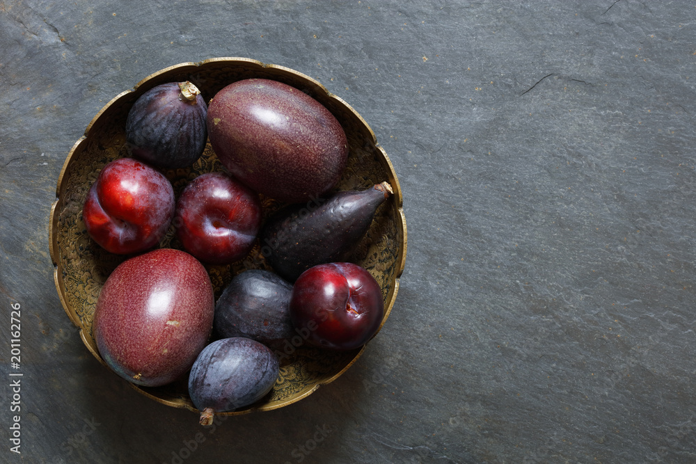 Dark Exotic Fruits on slate background including passion fruit, plums, figs, with copy space right Dark Exotic Fruits on slate background including passion fruit, plums, figs, with copy space right