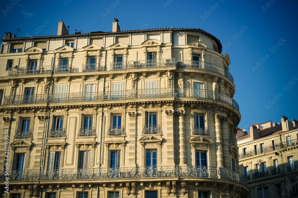 Old times building with tall windows and balconies on sunset in Marseille, France. March 2018