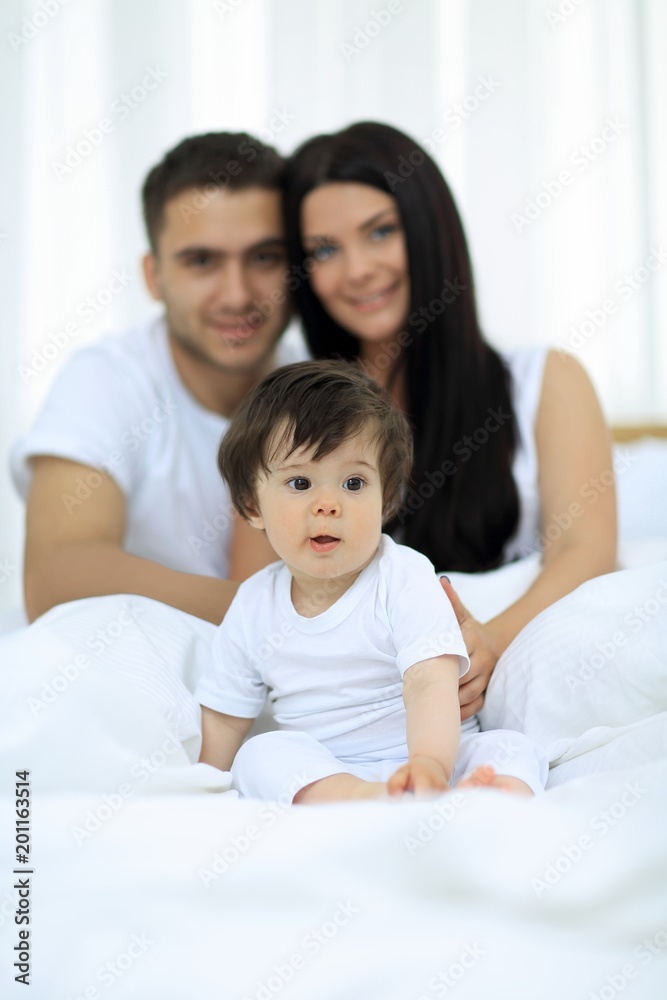 Happy couple and son sitting in bed