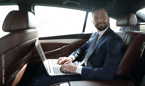 businessman with laptop sitting in the back seat of a car © ASDF