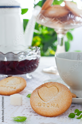 Homemade shortbread cookie with the inscription in Russian "Spring" on a summer white table with tea, selective focus