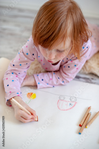 The girl draws in colored pencils