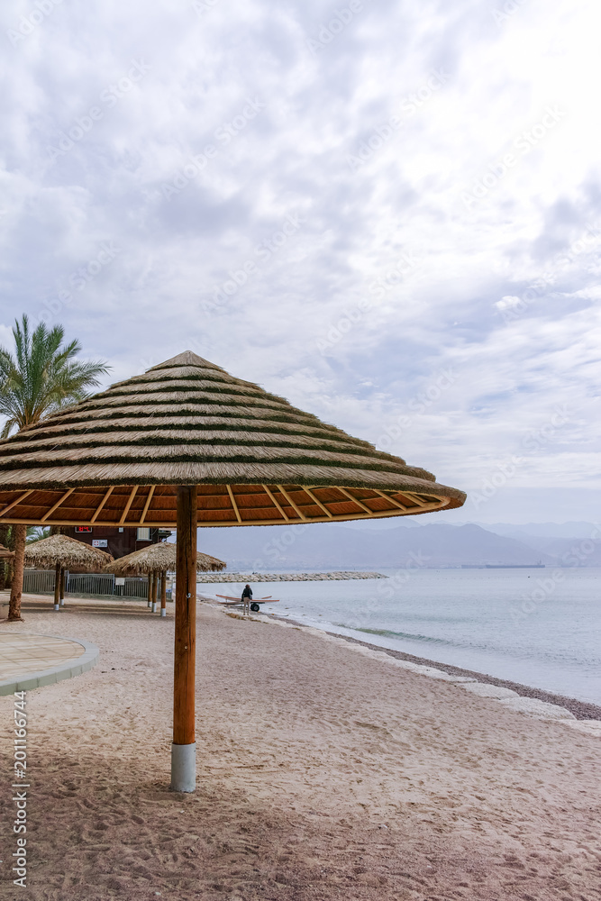 Beautiful public sandy beaches on Red Sea in Eilat with stro umbrellas, luxury vacation spa resorts in Israel