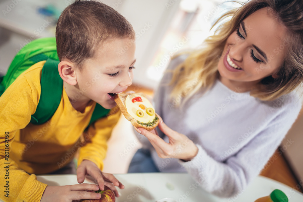 Mother making breakfast for her children in the morning and a snack for school Mother making breakfast for her children in the morning and a snack for school