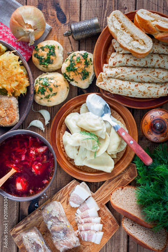 Traditional food in the Ukrainian cuisine - borsch, vareniki, bacon, broth, nalgovniki, cutlets in Kiev, dranniki, pampushki, on a wooden table, selective focus, top view