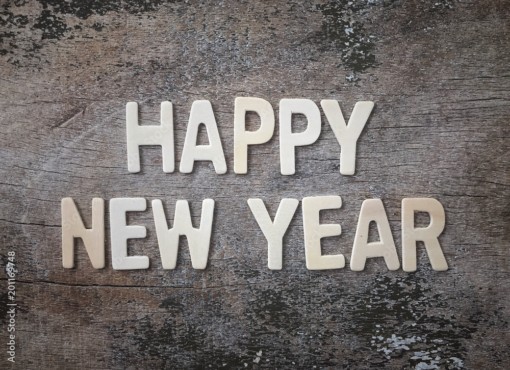 ‘Happy New Year’ wording made of wooden letters arranged on weathered old wooden table. ‘Happy New Year’ wording made of wooden letters arranged on weathered old wooden table.
