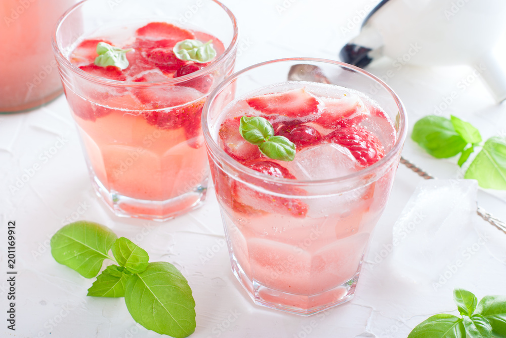 Fresh cool summer drink with strawberries and green basil in glass glasses on white table, horizontal, copy space Fresh cool summer drink with strawberries and green basil in glass glasses on white table, horizontal, copy space