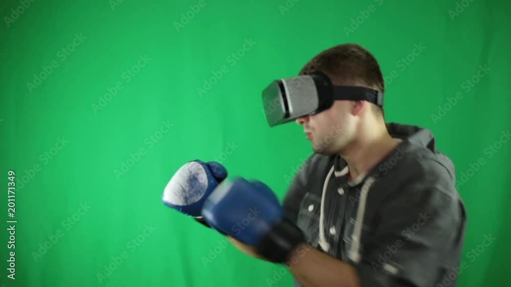 A man in virtual reality glasses and boxing gloves on a green background. A man in virtual reality glasses and boxing gloves on a green background.