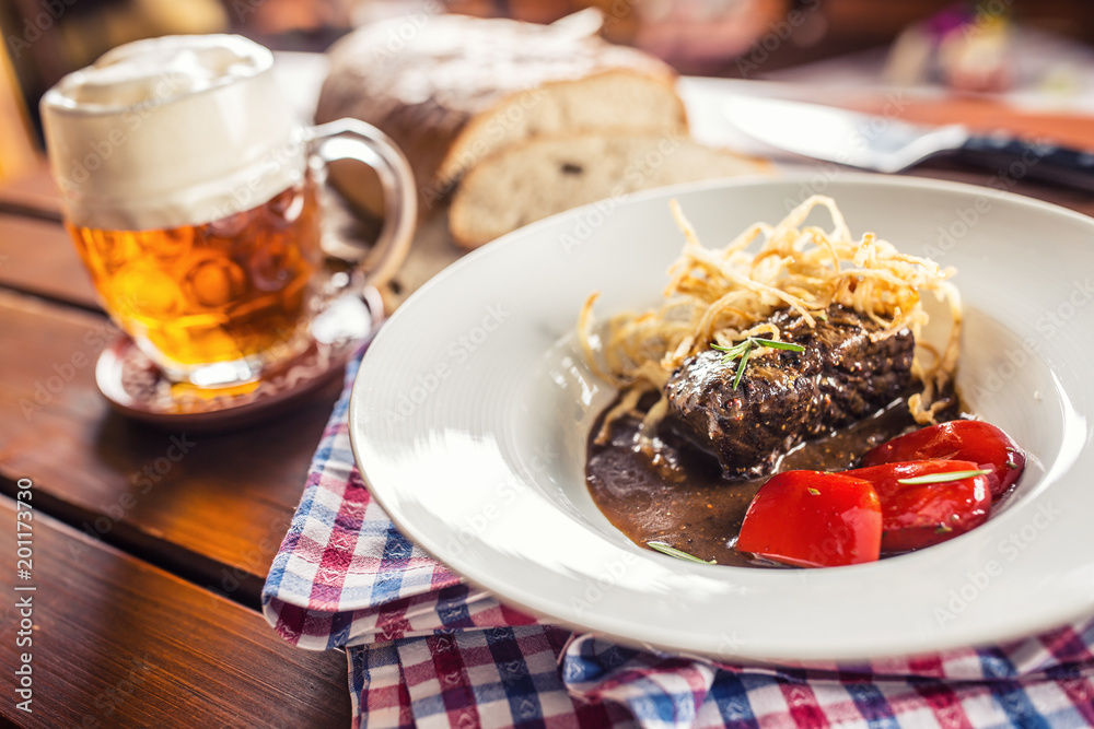 Confit beef steak with sauce fried onion bread draft beer and decoration in pub or restaurant Confit beef steak with sauce fried onion bread draft beer and decoration in pub or restaurant