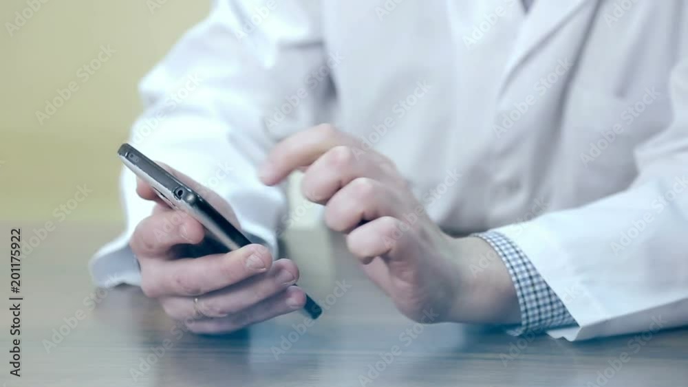 Doctor using a mobile phone and a tablet. A male doctor using electronic devices. Doctor using a mobile phone and a tablet. A male doctor using electronic devices.