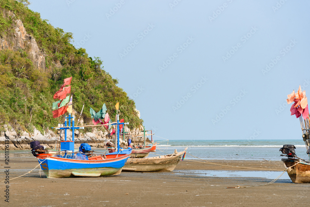 Fishing boats aground on the beach over sunny sky at Prachuap Khiri Khan, Thailand.