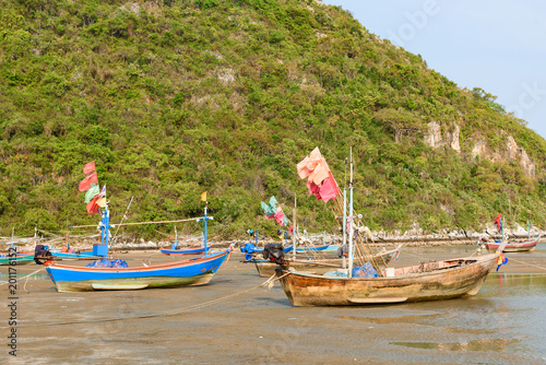 Fishing boats aground on the beach over sunny sky at Prachuap Khiri Khan, Thailand.