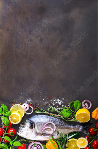 Fresh uncooked fish  dorado  sea bream with lemon  herbs  vegetables and spices on stone background. Top view. Banner