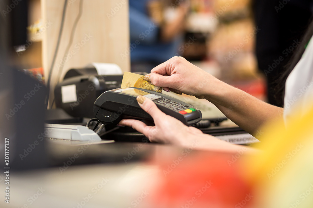 Woman hand with credit card swipe through terminal for sale, in market. Shopping and retail concept Woman hand with credit card swipe through terminal for sale, in market. Shopping and retail concept