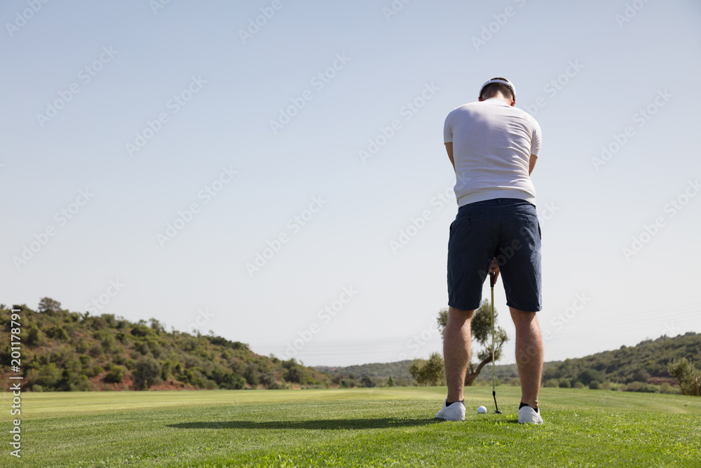 Rear view of golf player putting golf ball on the green Rear view of golf player putting golf ball on the green