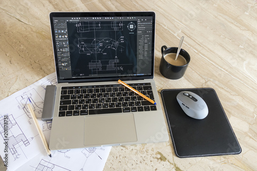 laptop with blueprints mechanical work desk photo