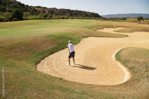 Golf player in sand trap hitting the ball photo