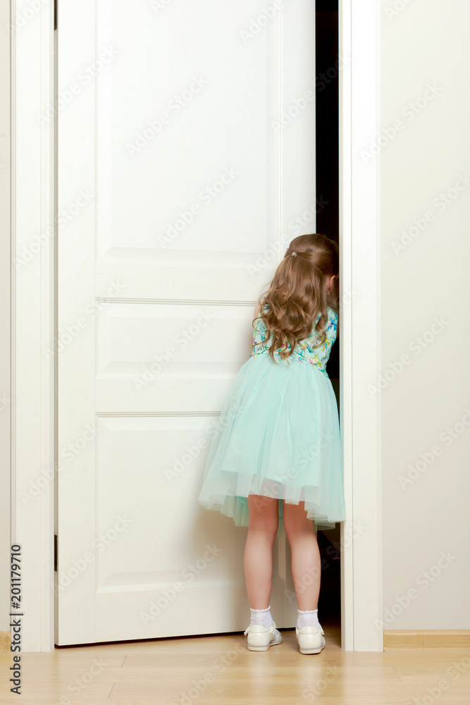 A little girl is standing by the door. A little girl is standing by the door.