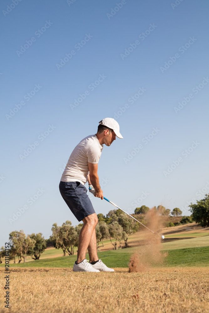 Golf player hitting golf ball in golf course Golf player hitting golf ball in golf course