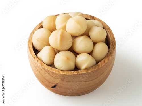 Macadamia nuts in wooden bowl on white background