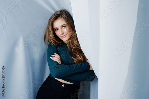 Handsome brunette girl wear on green, posing at curtains. Studio model portrait.