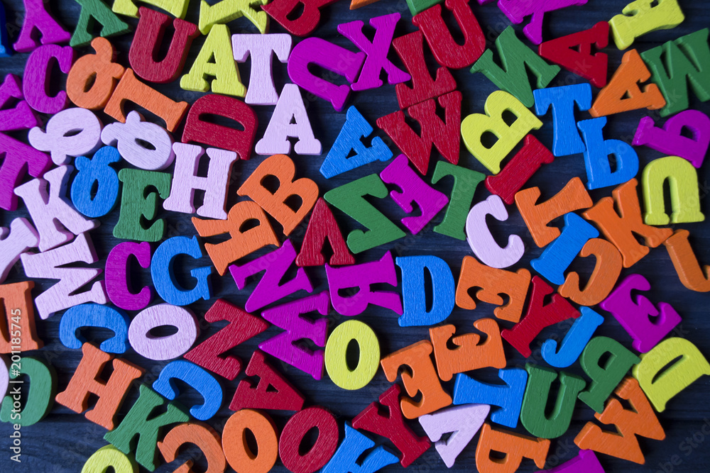 Multicolor letters on a dark blue wooden  background. Colorful wooden alphabet on a table.