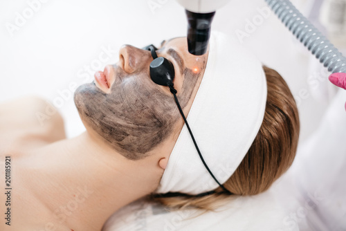 Laser Treatment and Skin Care. Side portrait of the beautiful woman with mask and safety goggles receiving the fraxel laser treatment.