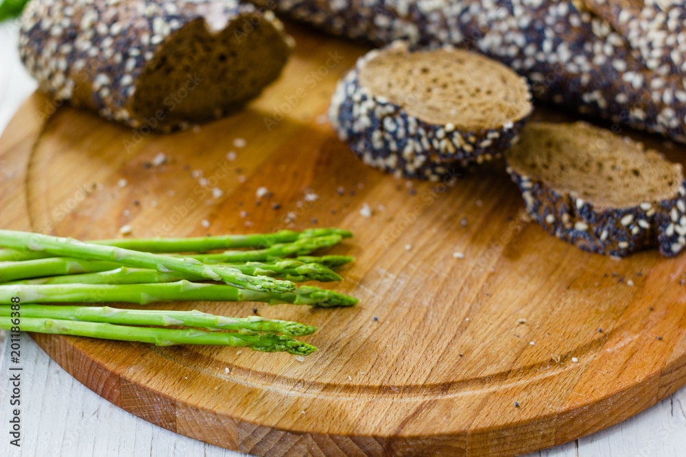 Fresh asparagus with hot bread on wooden kitchen board. Fresh asparagus with hot bread on wooden kitchen board.