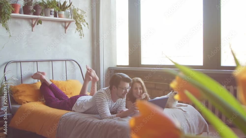 Happy young couple with french dog with laptop at home. Slow motion