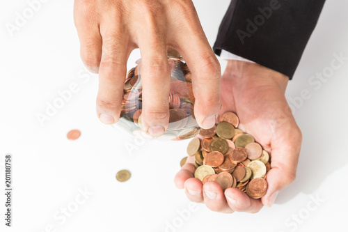 Businessman pouring coins fromn the glass to his hand, concept of saving money for finance accounting, growing business