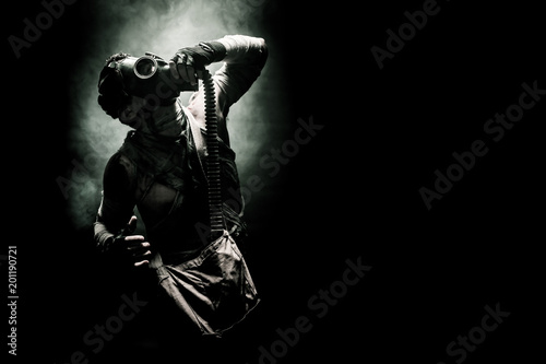 bandaged men in the gas mask on the black background surrounded by smoke and looking at the sky, survival soldier after apocalypse.