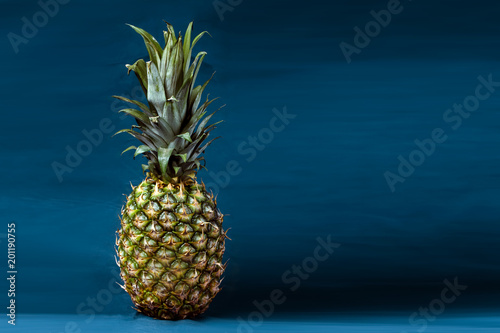 green pineapple on a blue background, vertical image