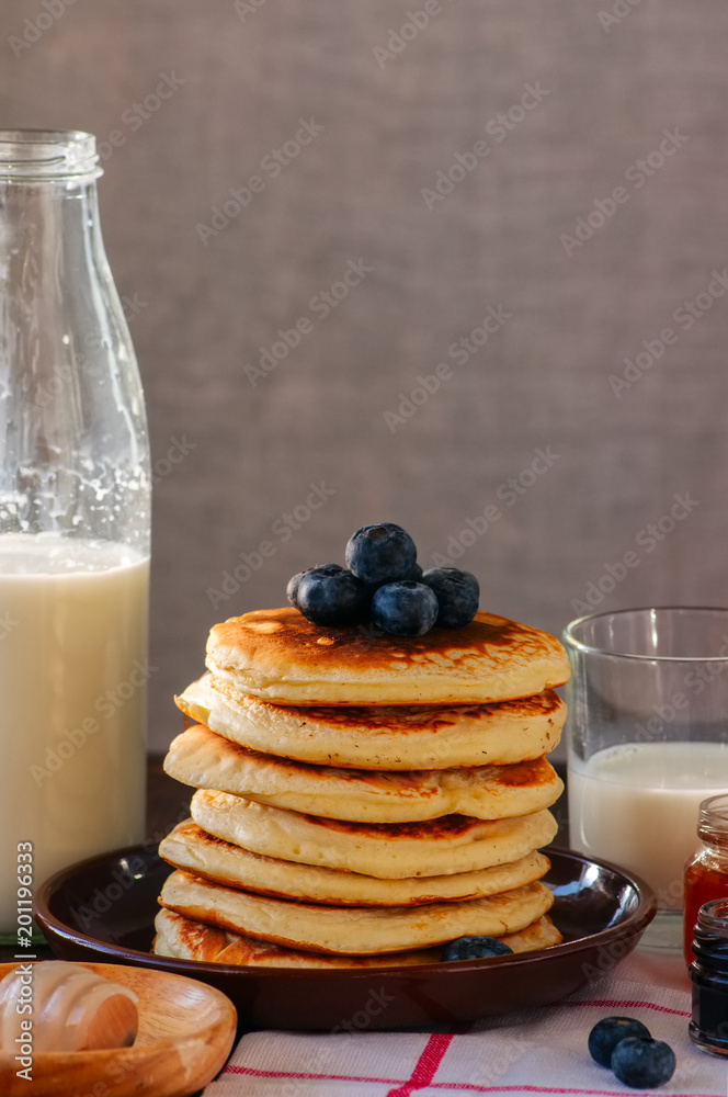 Stack of homemade pancakes with berries in a plate, milk in a jar, jam preserves. Rustic style. Wooden background. Stack of homemade pancakes with berries in a plate, milk in a jar, jam preserves. Rustic style. Wooden background.