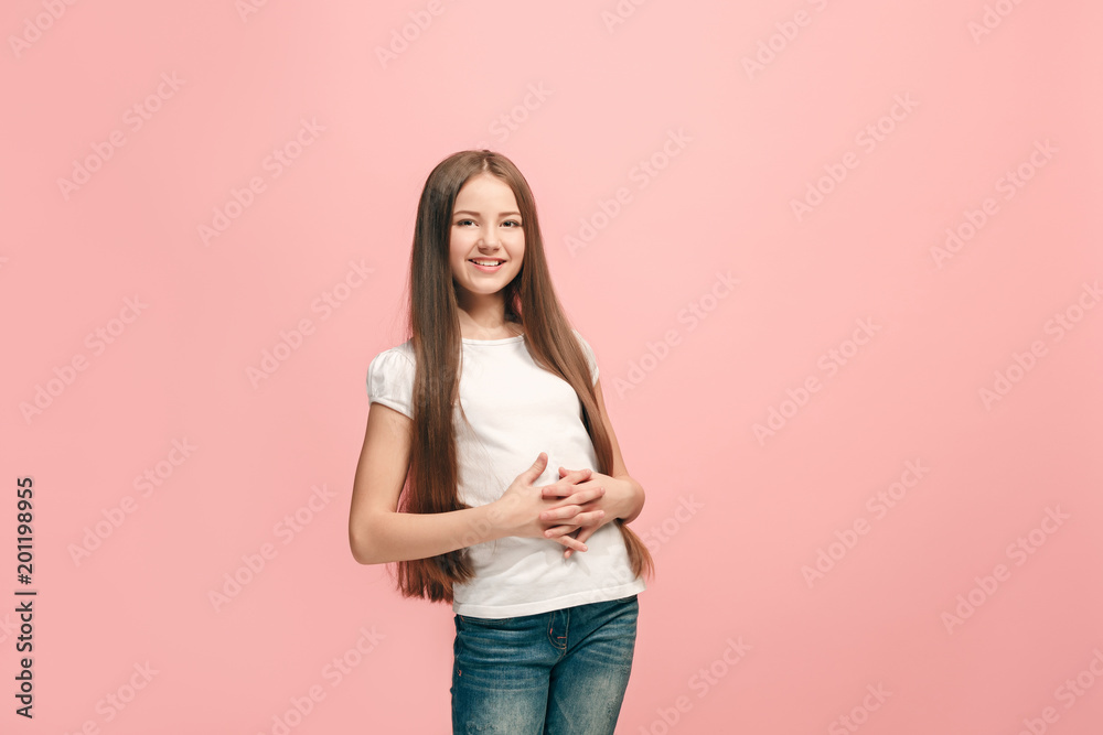 The happy teen girl standing and smiling against pink background. The happy teen girl standing and smiling against pink background.