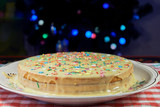 On the plate is a large biscuit cake made with their own hands. Delicious and sweet dessert for the holiday. The cake is decorated with stars and stripes of different colors.