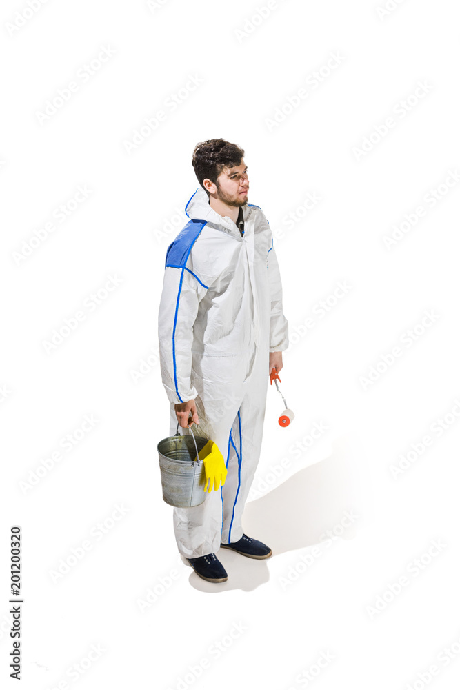 Young male decorator painting with a paint roller climbed a ladder isolated on white background. Young male decorator painting with a paint roller climbed a ladder isolated on white background.